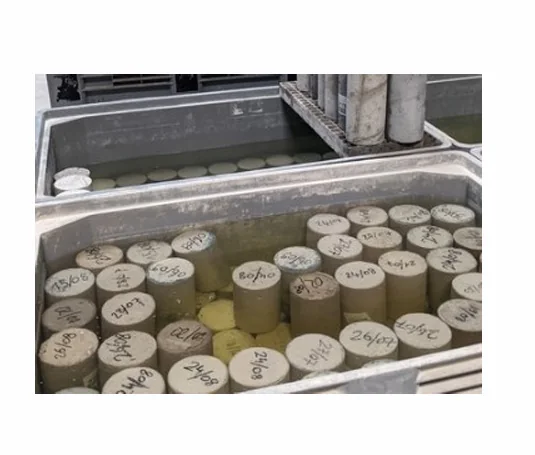 Éprouvettes cylindriques de béton identifiées immergées dans un bassin de conservation